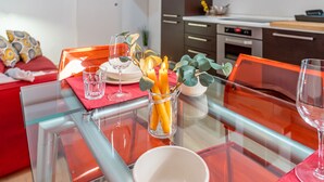 Una cocina moderna con una mesa de comedor de vidrio, sillas rojas y un sofá rojo.