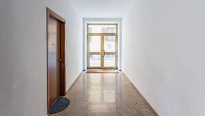 A hallway with a wooden door and a glass door leading outside. - Casa Elena (Pavia)