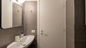A bathroom with a white sink, mirror, and door.