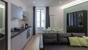 Un espace de vie compact comprenant un coin cuisine, un coin repas et un coin salon avec un canapé.