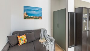 A modern living room with a grey sofa, a colorful geometric pillow, a book, and a grey throw blanket. A large framed picture of a cityscape hangs on the wall. - Casa Monti Mono (Pavia)