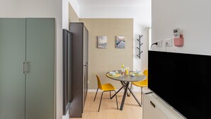 A modern kitchen with a built-in oven, a dining area with yellow chairs, and a flat-screen TV mounted on the wall. - Casa Monti Mono (Pavia)