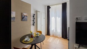 A dining area with a round table, chairs, and a TV in the corner. - Casa Monti Mono (Pavia)
