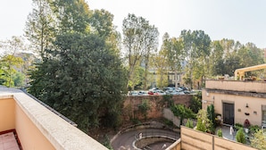 Terraço no terraço com um acesso circular, rodeado por árvores e uma área de estacionamento com carros.