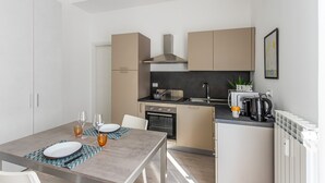 Una cuina moderna amb zona de menjador, que inclou una placa de cocció, forn, rentamigles i una cafetera.