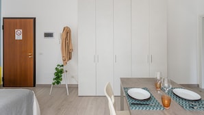 Una zona de menjador moderna amb una porta de fusta, un penjallabecs i una taula de dinar preparada amb plats, gots i coberts.