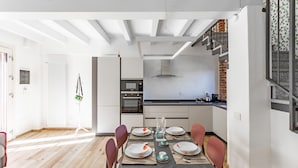 A modern kitchen with white cabinets, a built-in oven, and a stainless steel range hood. - Casetta Cascina Rizzo (Pavia)