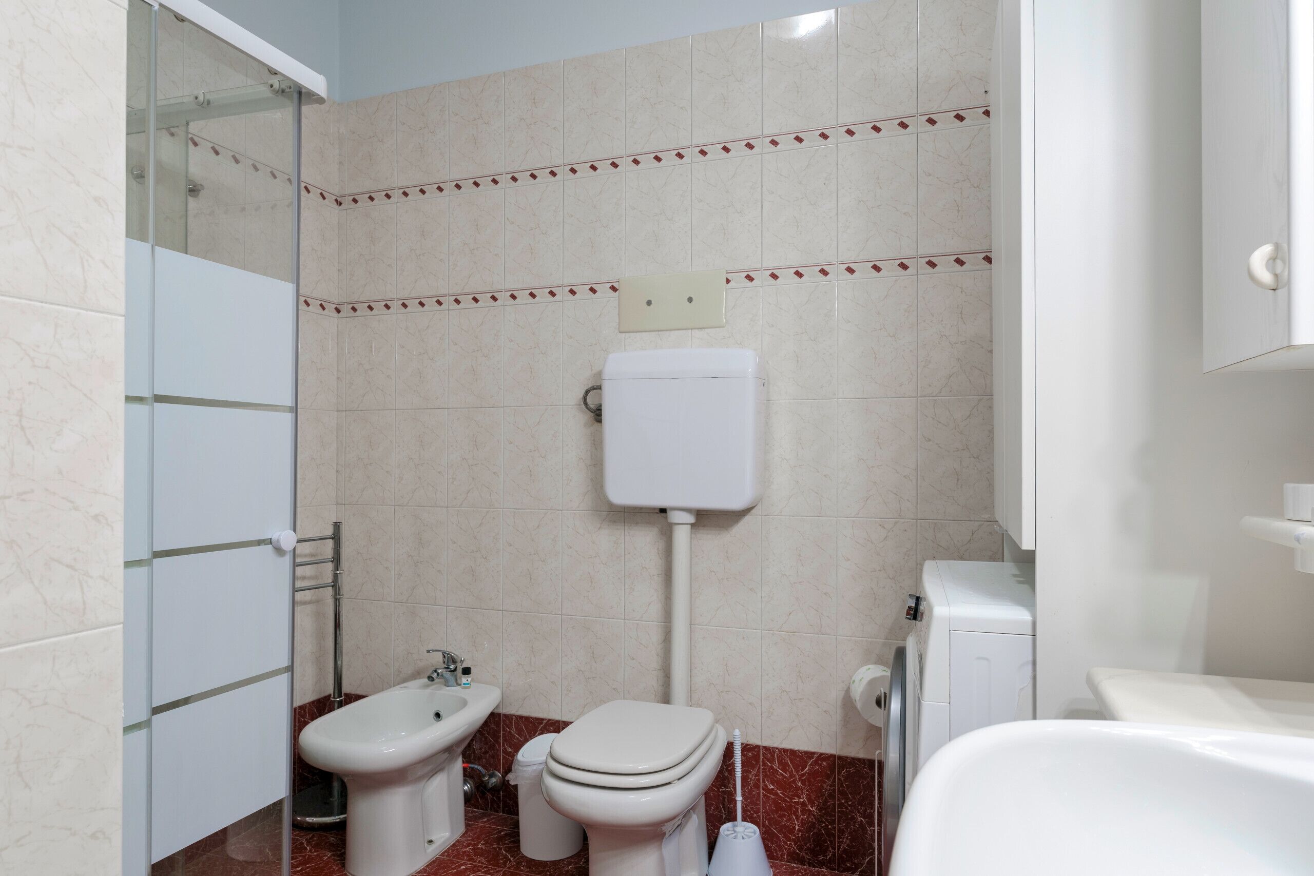 A bathroom with a toilet, bidet, and a washing machine.
