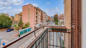 A balcony overlooking a street with buildings, a fence, and a parked car. - Via Cremona (Brescia)