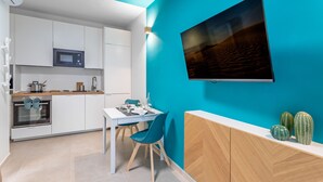 Une cuisine moderne avec des meubles blancs, un four à micro-ondes et un coin repas comprenant une table et des chaises.