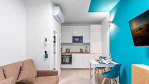 Une cuisine moderne avec des meubles blancs, un four à micro-ondes et un coin repas comprenant une table et des chaises.