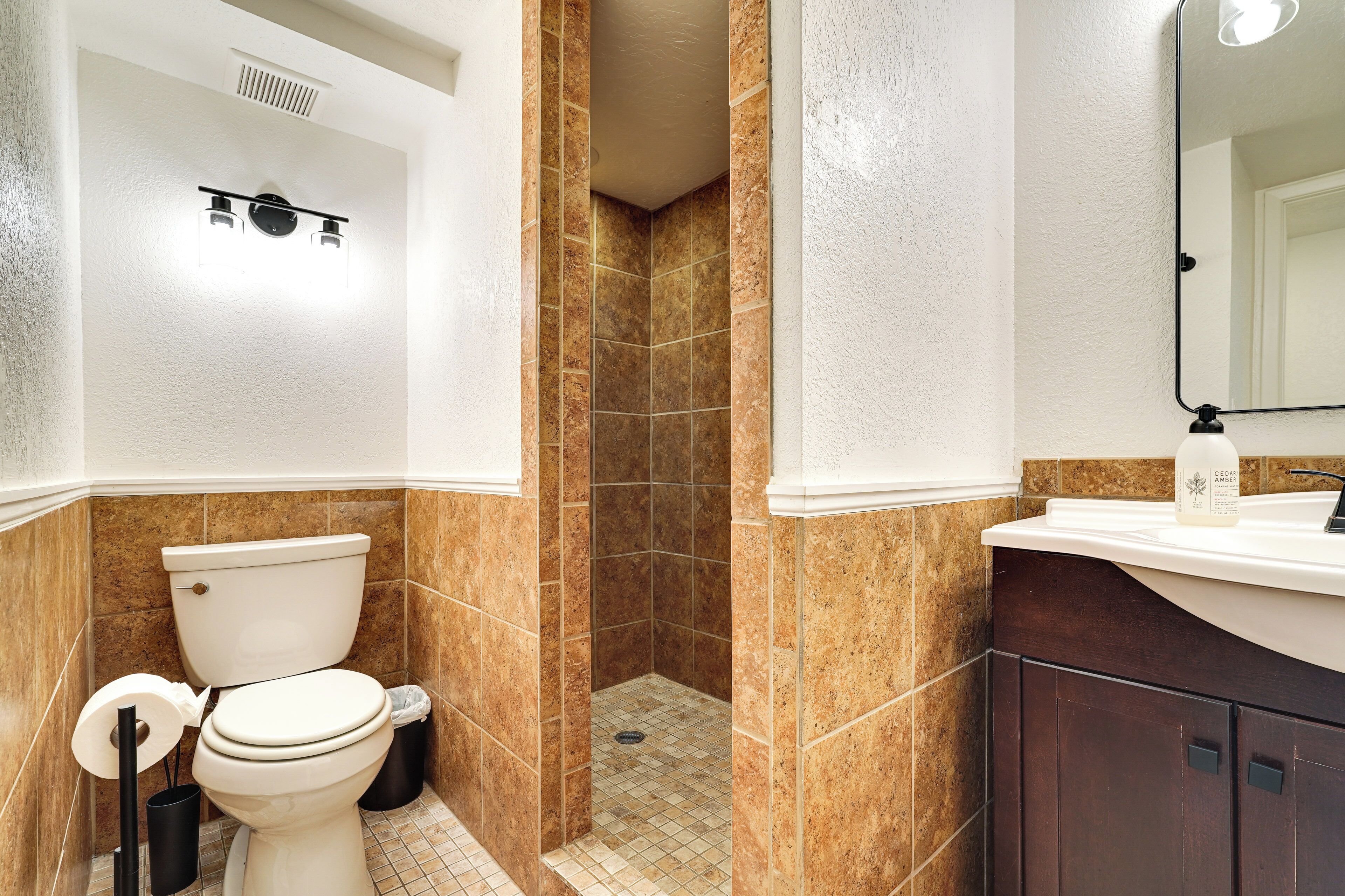 Un baño con inodoro, cabina de ducha y lavabo con espejo.