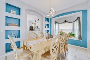 A dining area with a wooden table, chairs, and blue shelving. - 7 Mi to Disney: Kissimmee Home w/ Pool & Hot Tub! (Kissimmee)