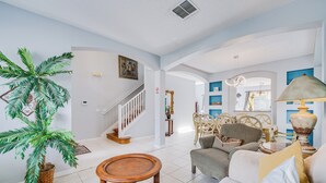 A spacious living room with a staircase, a dining area, and a large potted plant. - 6BR Disney Villa Pool, Spa & Game Room (Kissimmee)