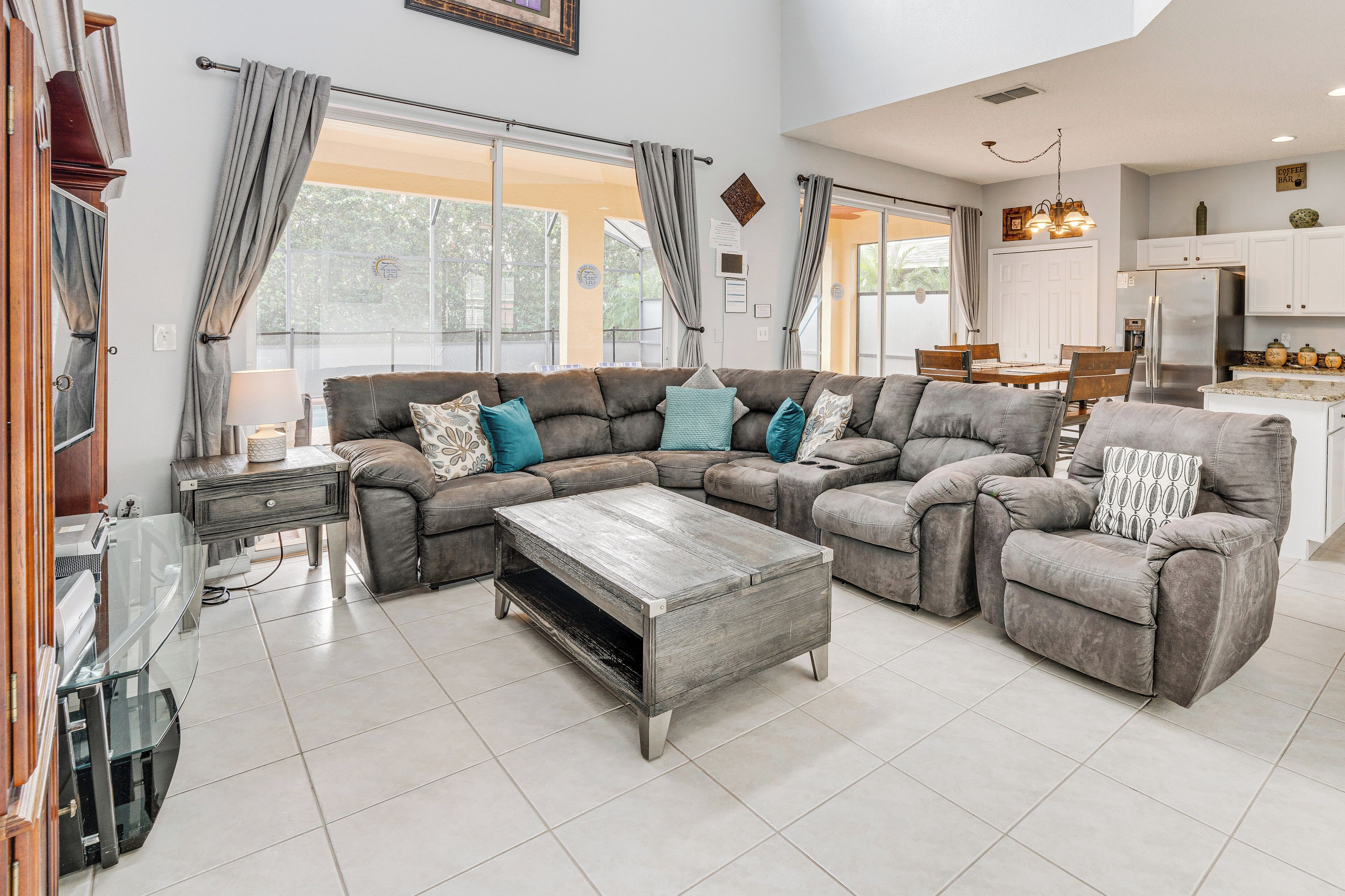 A spacious living room with a sectional sofa, a coffee table, and a dining area with a kitchen in the background.