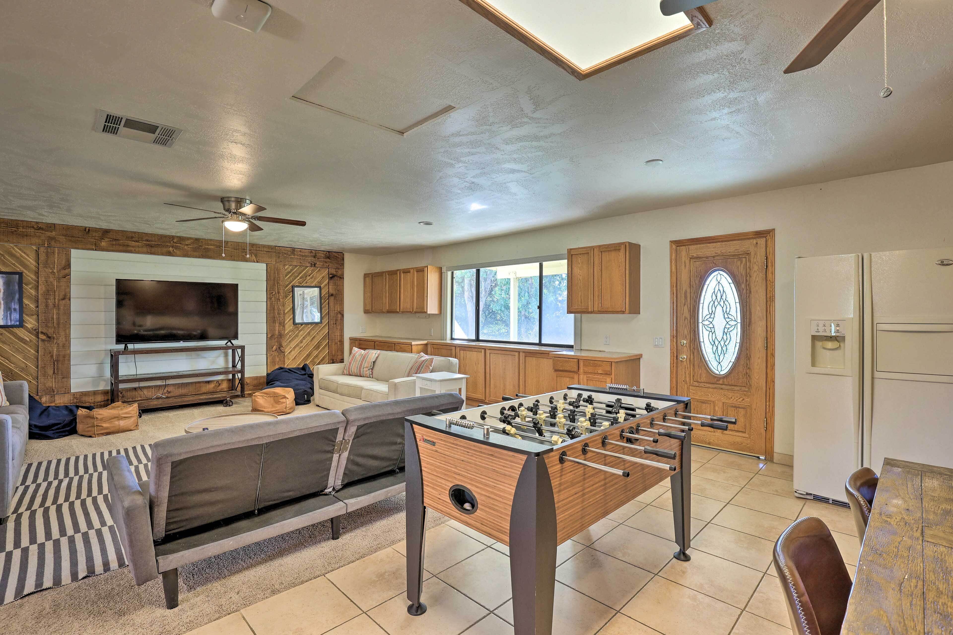 A modern living room with a foosball table, a flat-screen TV, and a cozy seating area.