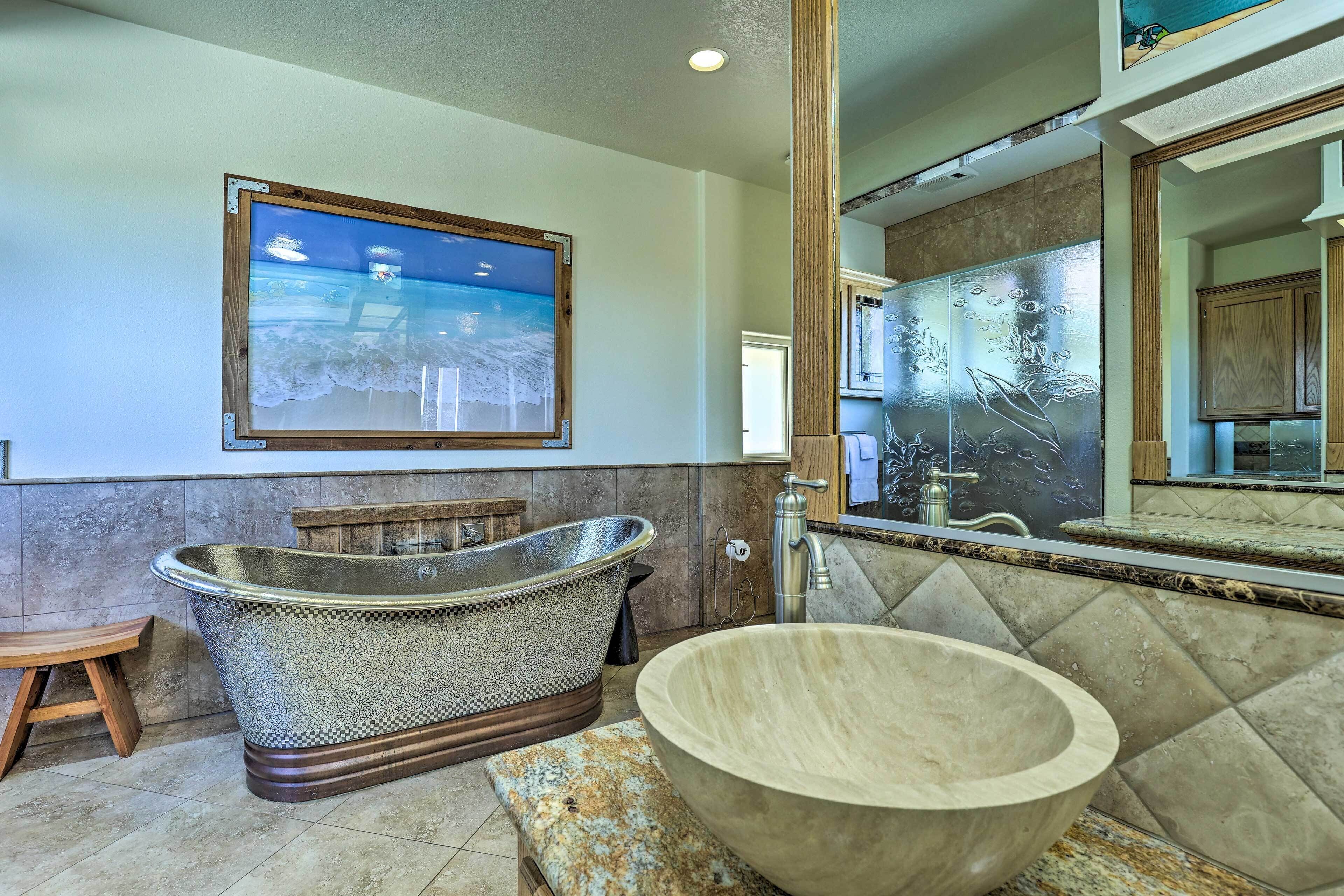 A bathroom with a freestanding bathtub, a large wooden bowl sink, and a wall-mounted mirror.