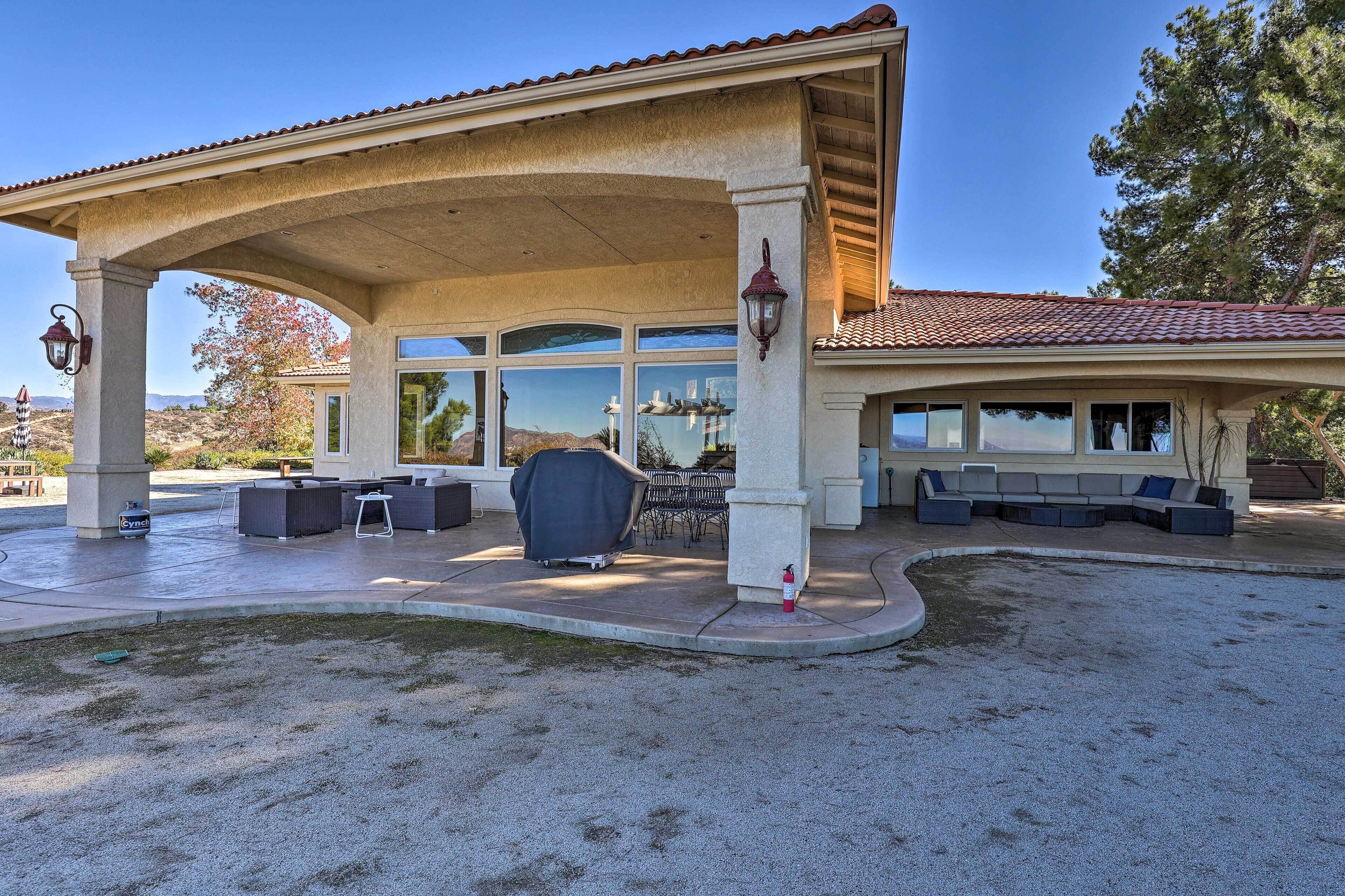 A covered patio area with outdoor seating, a fire extinguisher, and a view of the surrounding landscape.