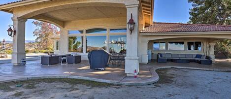 A covered patio area with outdoor seating, a fire extinguisher, and a view of the surrounding landscape.