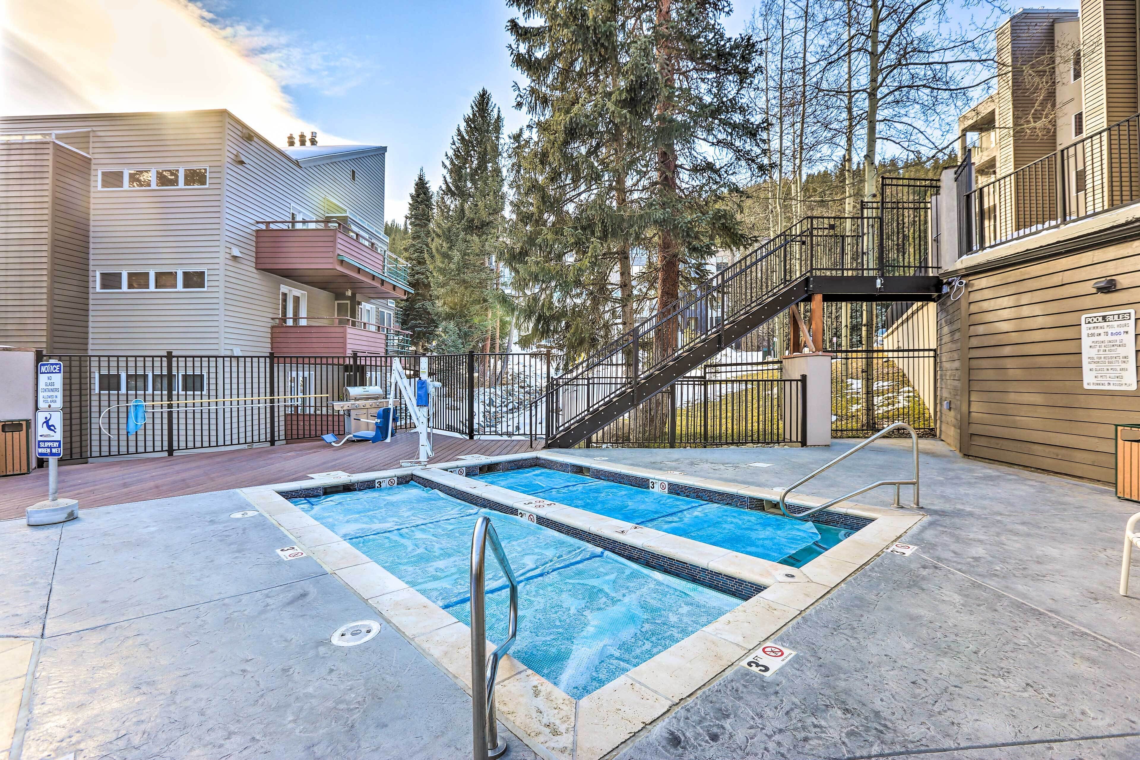 Zona de piscina con dos piscinas, una escalera y un edificio con balcones.