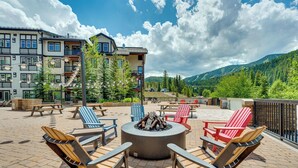 Une terrasse sur le toit, dotée d’un espace extérieur aménagé et d’un foyer, offrant une vue sur un paysage montagneux.