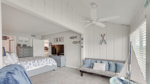 Un dormitorio con cama, sofá, ventilador de techo y ventana con persianas.