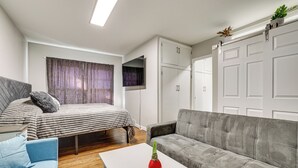 A modern bedroom with a bed, a grey sofa, a white table, and a wardrobe. - Charming Nampa Retreat w/ Patio: 20 Mi to Boise! (Nampa)