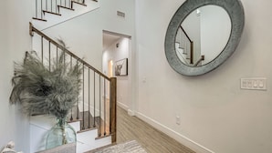 A staircase with wooden railings, a glass vase with dried plants, and a round mirror on the wall. - Family-friendly Near Busch Gardens, USF & More (Lutz)