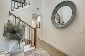 A staircase with wooden railings, a glass vase with dried plants, and a round mirror on the wall. - 3 Mi to Usf: Dog-friendly Home w/ Large Yard (Lutz)
