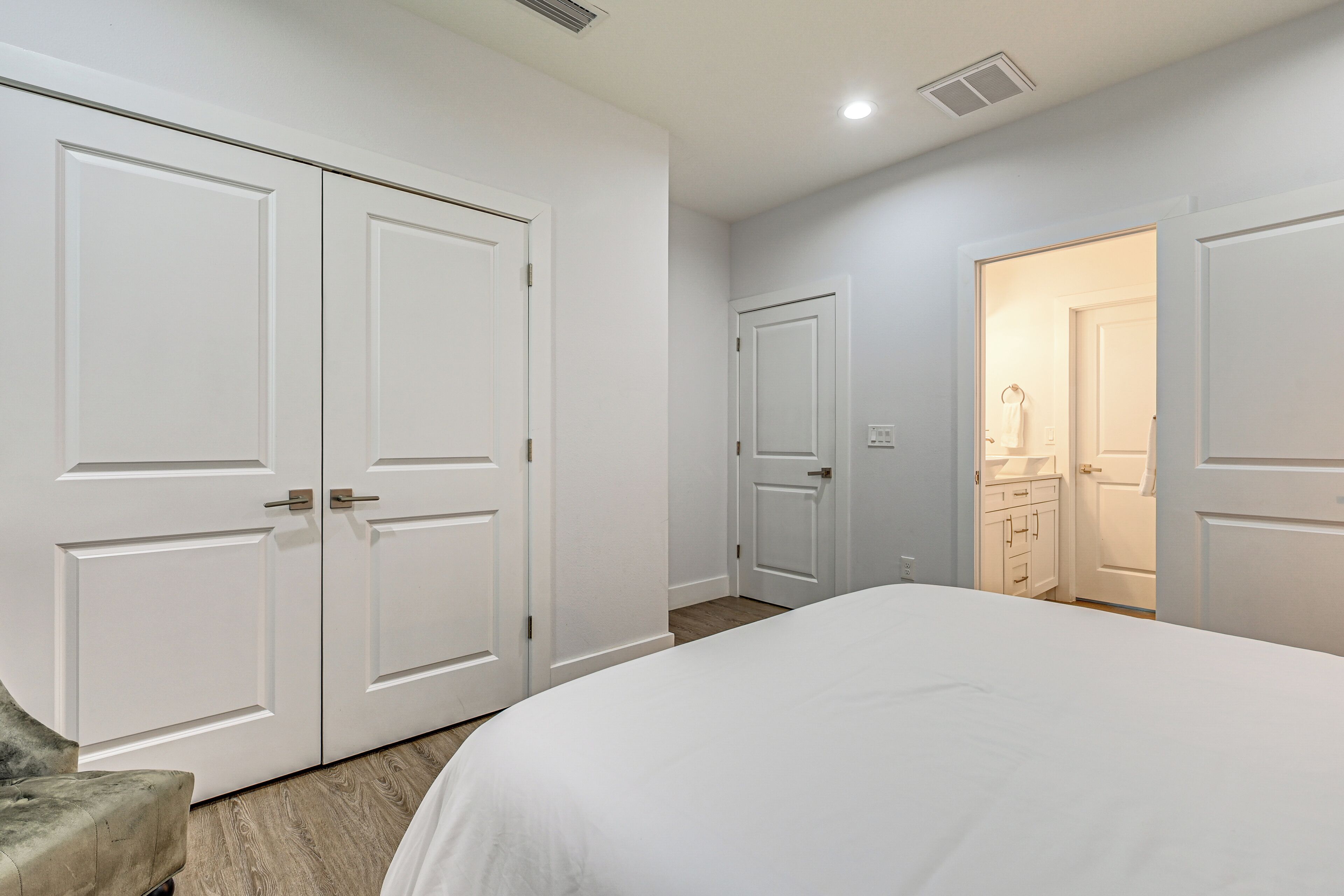 Un dormitorio con una cama grande, un armario y un baño visible a través de una puerta abierta.