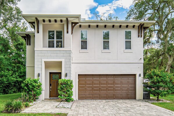 A two-story house with a garage, a front door, and a small front yard with plants. - 3 Mi to Usf: Dog-friendly Home w/ Large Yard (Lutz)