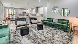 A modern living room with a green sofa, black ottoman, and a furry rug. - Family-friendly Near Busch Gardens, USF & More (Lutz)