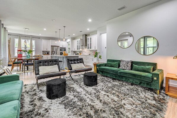 A modern living room with a green sofa, black ottoman, and a furry rug. - Modern Home Pet Friendly Kids Playroom More! (Lutz)