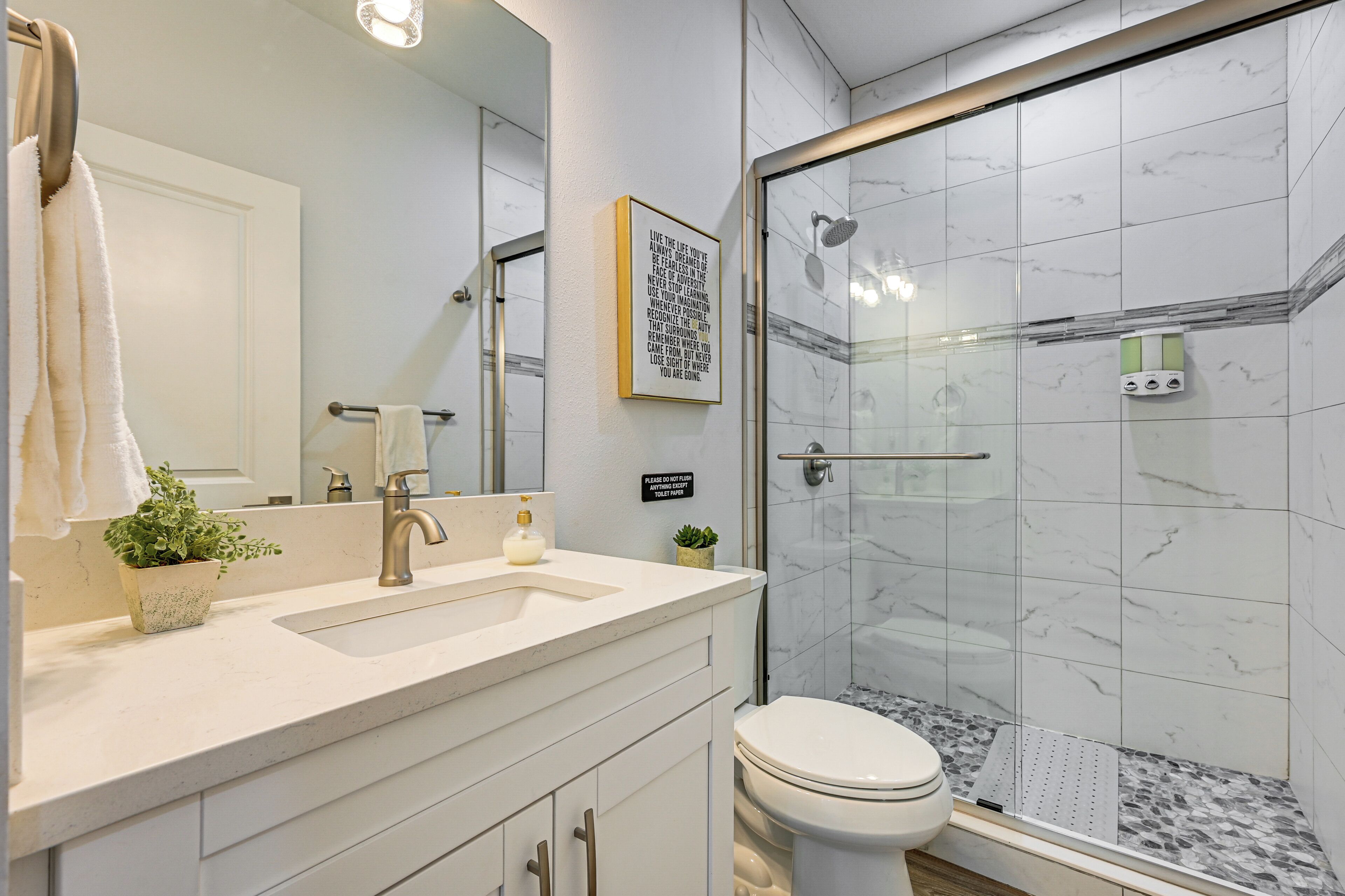A modern bathroom with a glass shower enclosure, a sink with a towel rack, and a toilet.