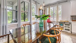 A dining area with a wooden table, chairs, a vase with a plant, and a kitchen area with cabinets and a countertop. - Family-friendly Near Busch Gardens, USF & More (Lutz)