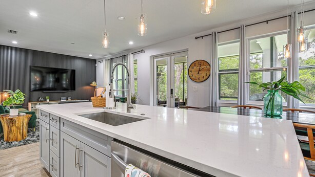 A modern kitchen with a large island, a built-in TV, and large windows. - Family-friendly Near Busch Gardens, USF & More (Lutz)