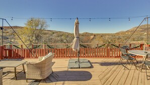 A wooden deck with outdoor furniture, a table, and an umbrella. - Medicine Park Getaway: Kayaks, Deck & Mtn Views! (Medicine Park)