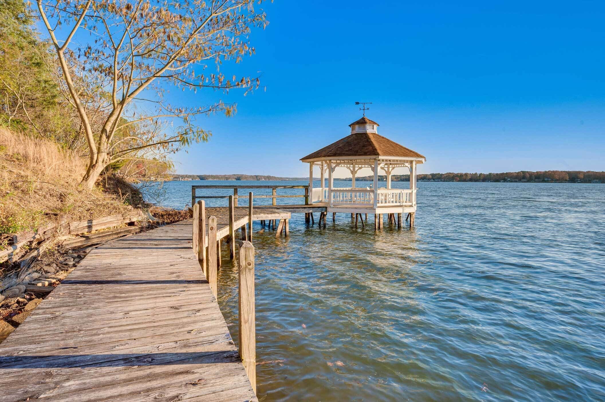 A wooden pier leading to a gazebo by a calm lake.