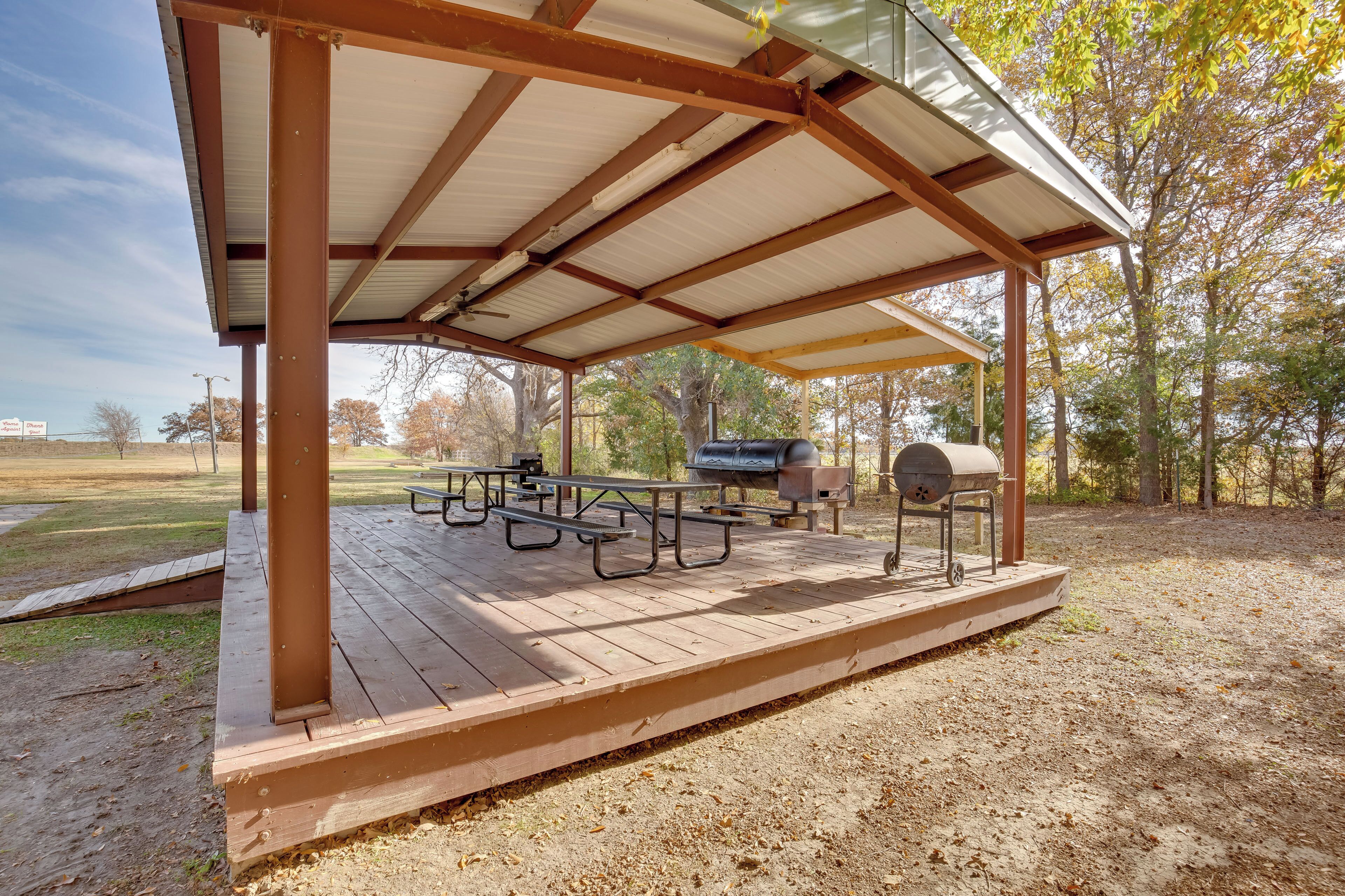 A covered picnic area with picnic tables and a barbecue grill.