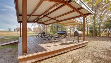 A covered picnic area with picnic tables and a barbecue grill.