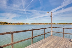 A wooden pier extending into a calm body of water with a clear sky above.