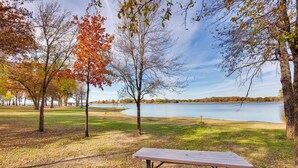 A picnic table in a park with trees and a lake. - On-site Fishing Pier: Pet-friendly Kerens Cabin! (Kerens)