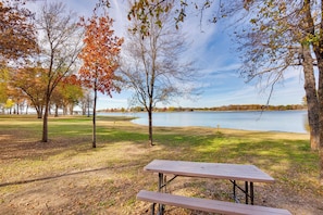 A picnic table in a park with trees and a lake in the background.