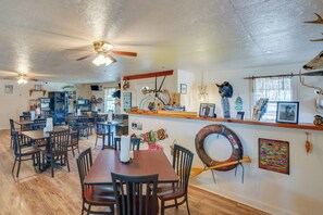 A dining area with wooden tables and chairs, ceiling fans, and various wall decorations including animal skulls and a surfboard. - On-site Boat Ramp: Pet-friendly Kerens Studio! (Kerens)