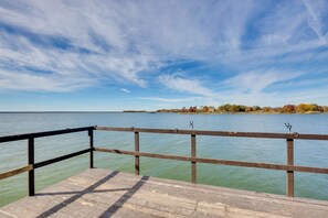 Une jetée en bois, dotée d’une rambarde qui s’étend au-dessus de l’eau calme.