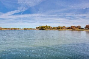 Un lac paisible, bordé d’arbres, avec un bâtiment visible au loin.
