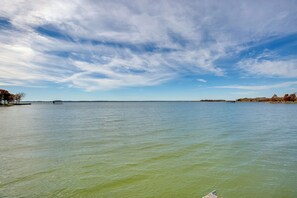 Un plan d’eau paisible, avec une jetée qui s’avance sur l’eau, entouré d’arbres et sous un ciel dégagé.
