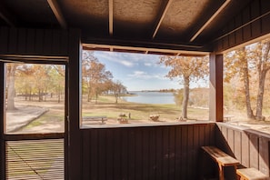 A cabin with a large window overlooking a lake and park. - Community Pier: Cozy Kerens Cabin! (Kerens)