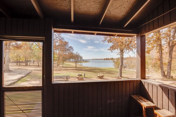A cabin with a large window overlooking a lake and park.