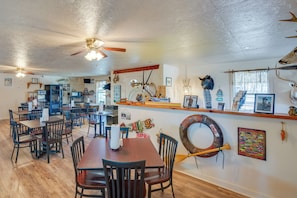A dining area with multiple tables and chairs, ceiling fans, and various wall decorations including animal skulls and a large fish. - Community Pier: Cozy Kerens Cabin! (Kerens)
